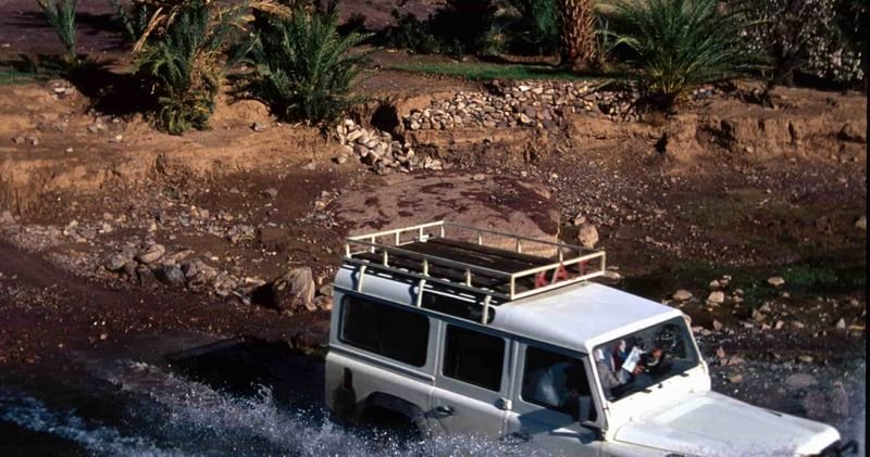 4x4 blanc chargé de bagages traversant un cours d’eau dans le Sud marocain